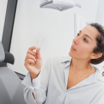 mujer joven observa alineador transparente sentada en el sillón del gabinete dental